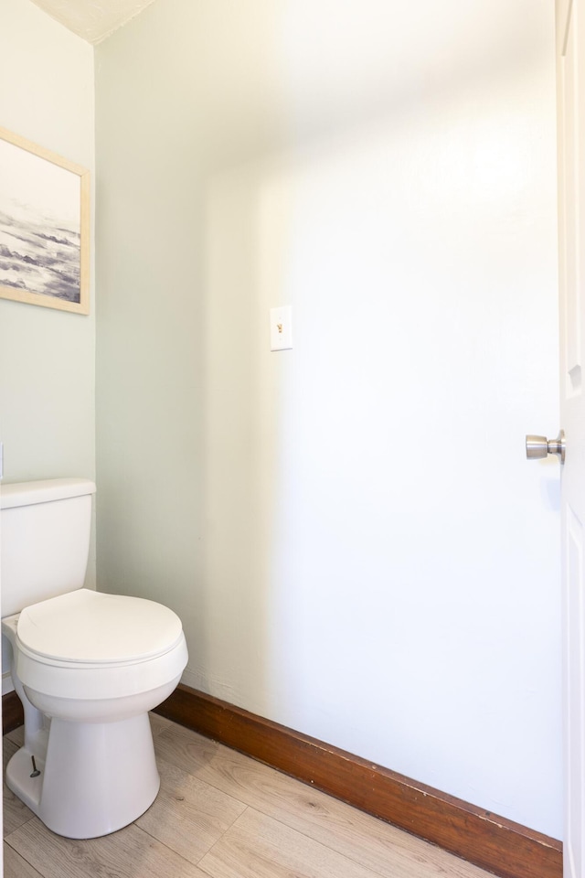 bathroom with baseboards, wood finished floors, and toilet