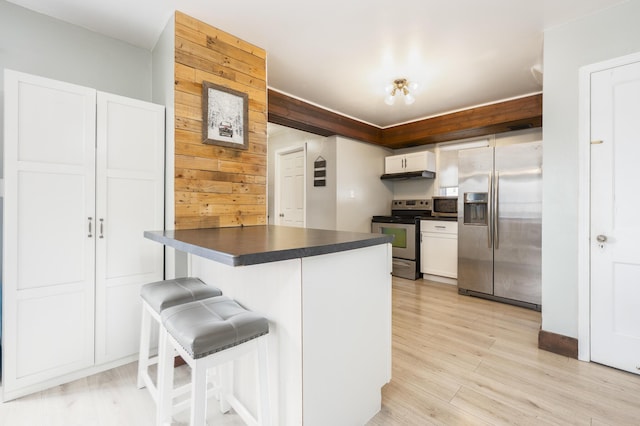 kitchen featuring white cabinetry, dark countertops, a kitchen bar, and stainless steel appliances