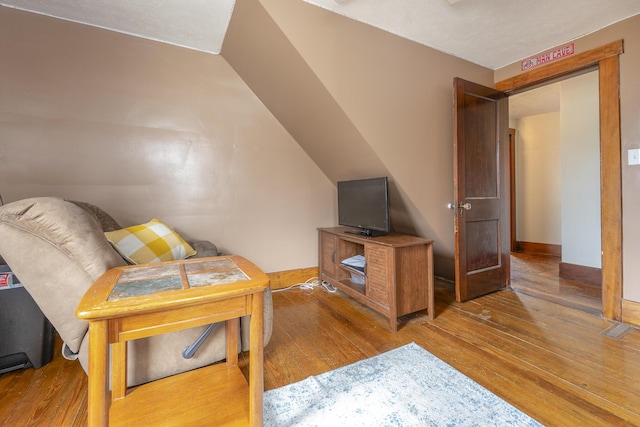 living room with hardwood / wood-style floors, baseboards, lofted ceiling, and visible vents