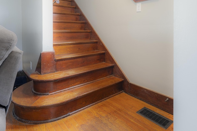 staircase with visible vents and wood finished floors