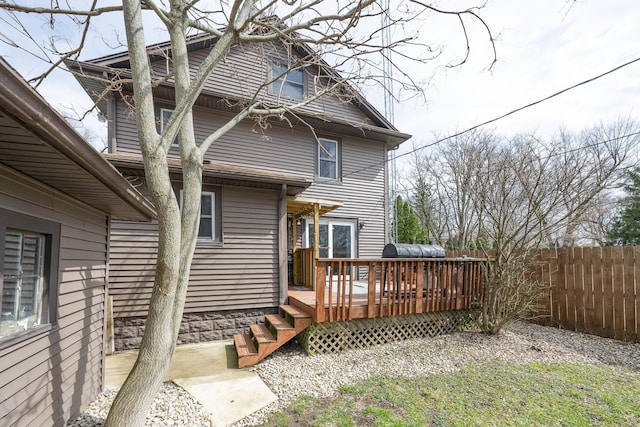 rear view of house with a wooden deck and fence