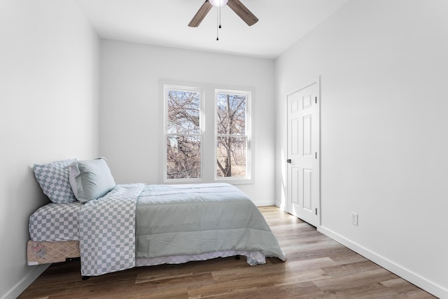 bedroom featuring ceiling fan, baseboards, and wood finished floors