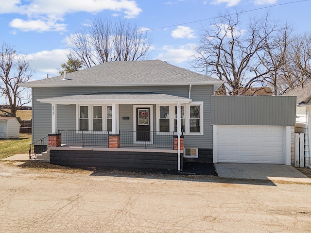 bungalow featuring roof with shingles, covered porch, concrete driveway, and an attached garage