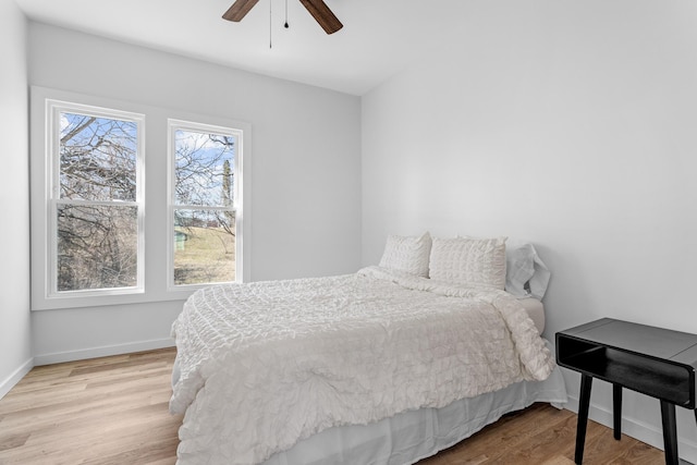 bedroom with ceiling fan, baseboards, and wood finished floors