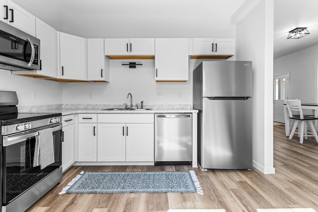 kitchen with baseboards, light wood finished floors, a sink, white cabinets, and appliances with stainless steel finishes