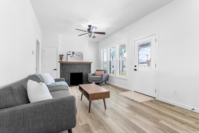 living room featuring light wood-type flooring, baseboards, a ceiling fan, and a fireplace