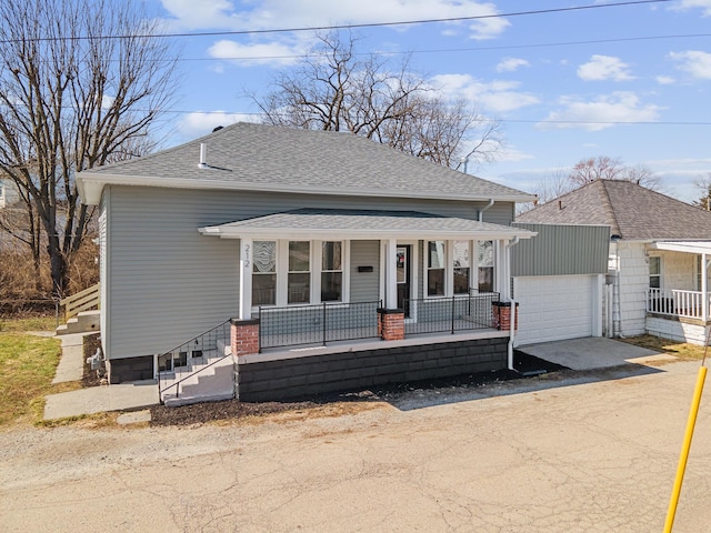 bungalow featuring a porch, an outbuilding, driveway, and roof with shingles