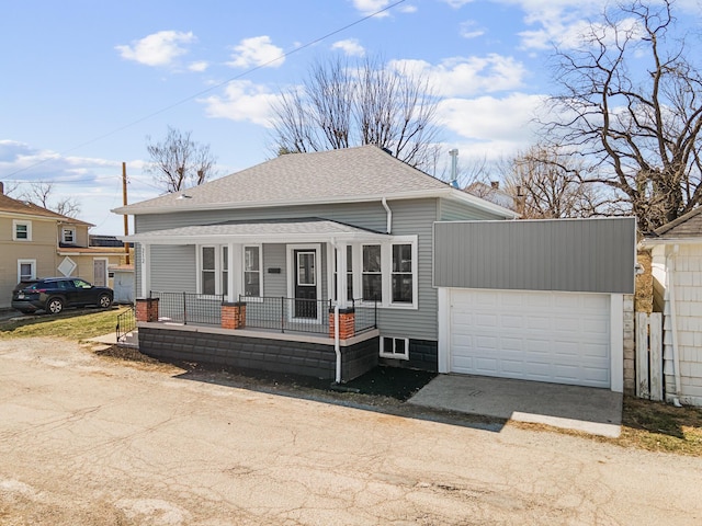 view of front facade with a porch, driveway, and roof with shingles