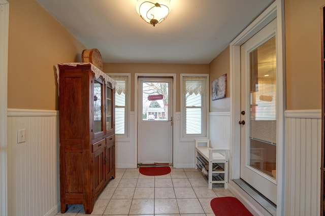 foyer featuring light tile patterned floors and a wainscoted wall