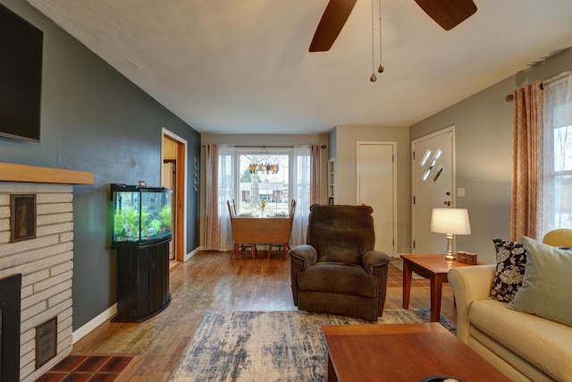 living room with a fireplace, baseboards, ceiling fan, and wood finished floors