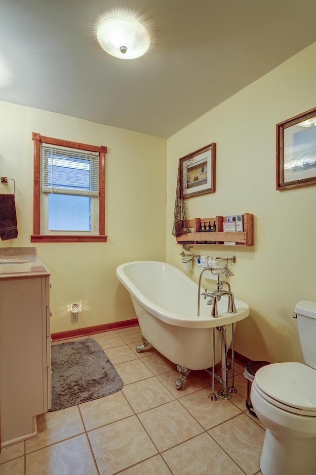 bathroom featuring tile patterned flooring, a freestanding tub, toilet, and baseboards