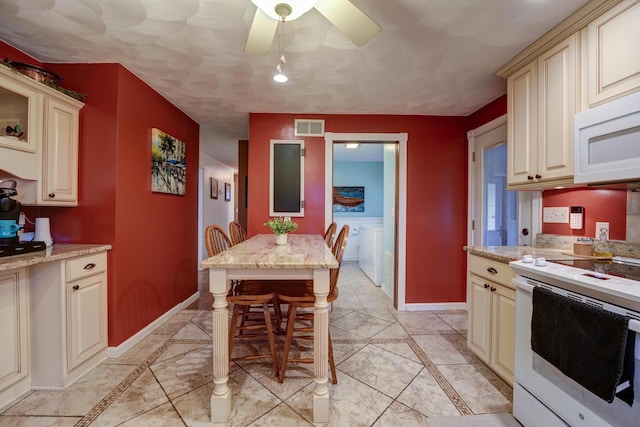 kitchen with white appliances, cream cabinets, visible vents, and washer and clothes dryer