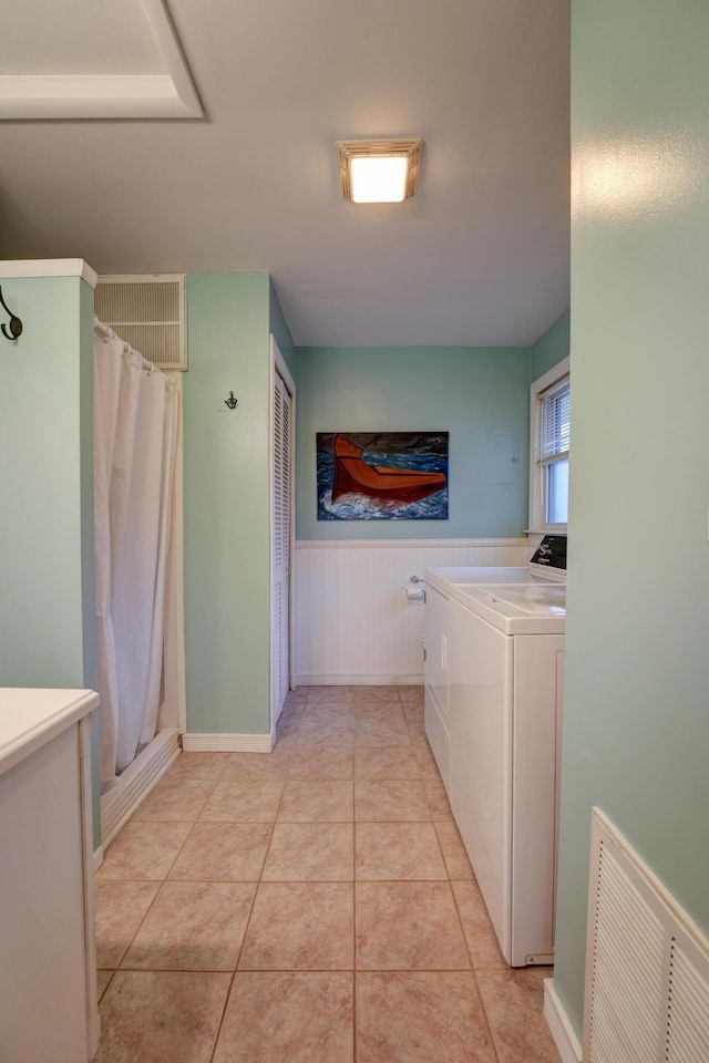 clothes washing area with washing machine and clothes dryer, visible vents, light tile patterned floors, laundry area, and wainscoting