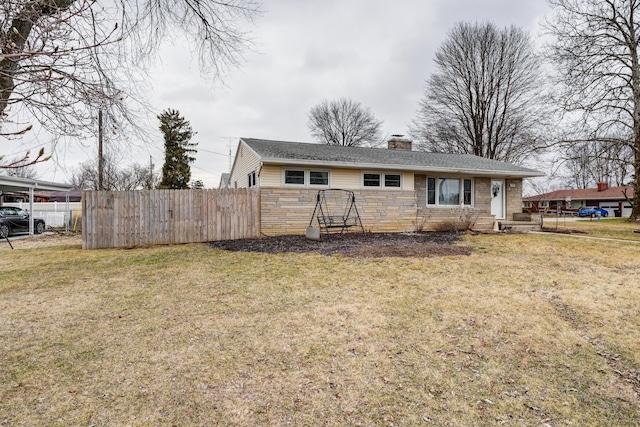 rear view of house featuring stone siding, a lawn, a chimney, and fence