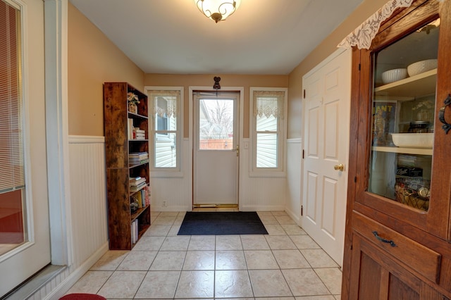 foyer entrance with light tile patterned floors and wainscoting