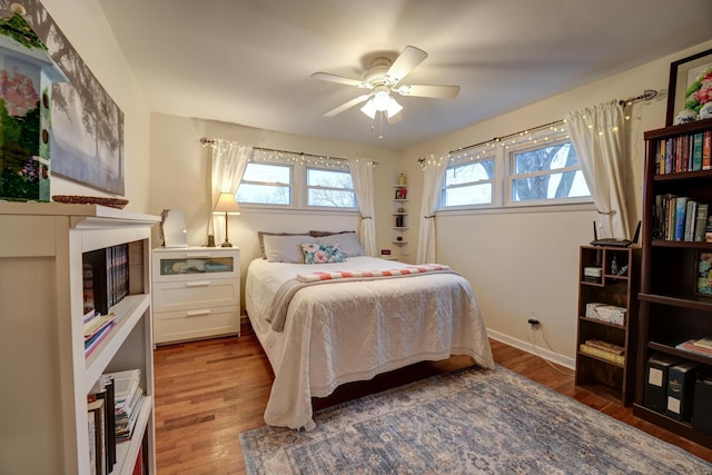 bedroom with ceiling fan, baseboards, and wood finished floors