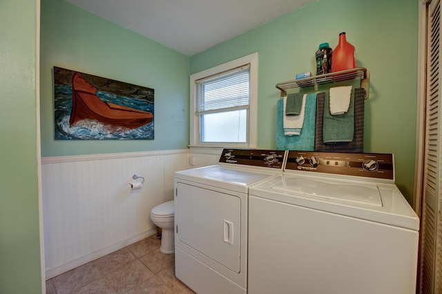 laundry room with laundry area, light tile patterned floors, washing machine and dryer, and a wainscoted wall