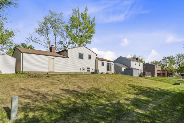 rear view of property with a storage unit, a yard, an outbuilding, and a chimney