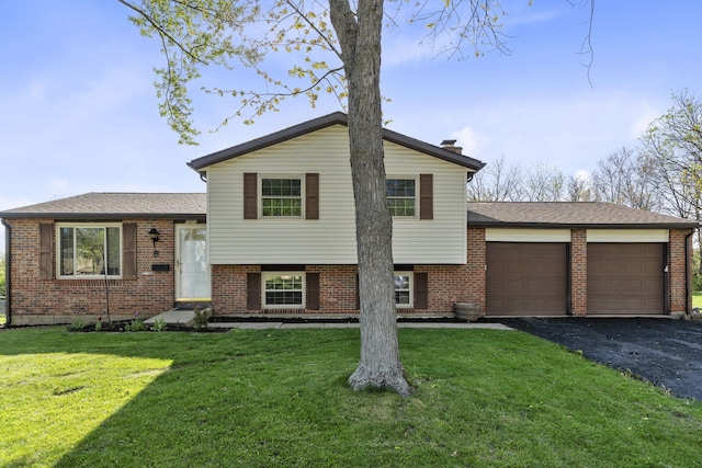 split level home with brick siding, driveway, a front yard, and a garage