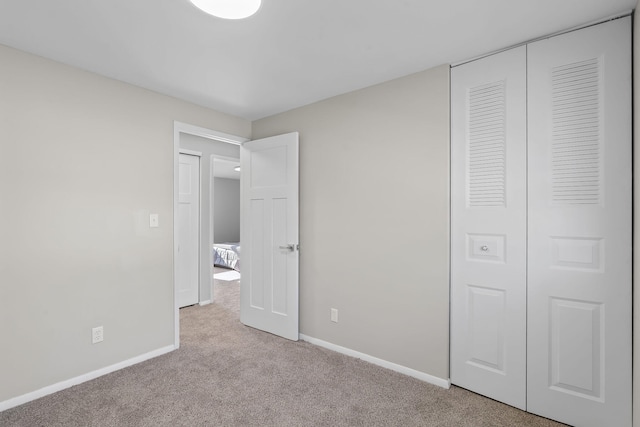 unfurnished bedroom with baseboards, carpet flooring, and a closet