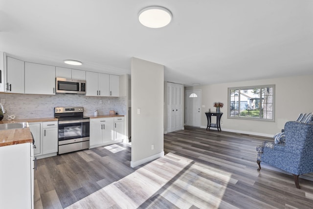 kitchen with dark wood-style flooring, a sink, wood counters, stainless steel appliances, and open floor plan