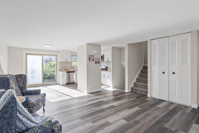 living area with stairs, baseboards, and wood finished floors