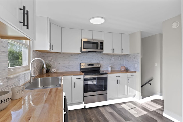 kitchen featuring a sink, stainless steel appliances, white cabinetry, backsplash, and butcher block counters