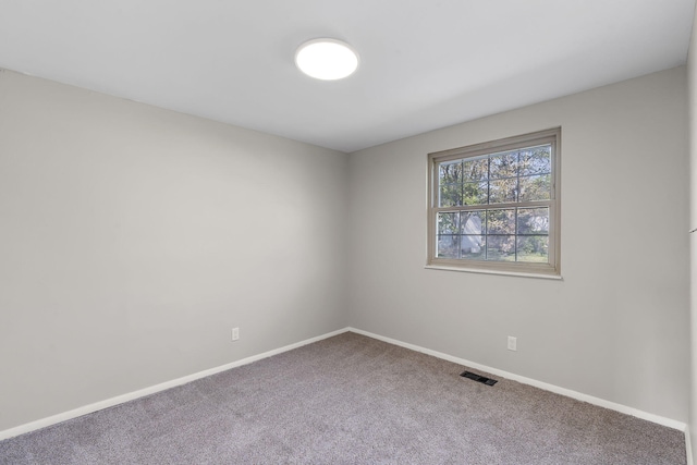 carpeted empty room featuring baseboards and visible vents