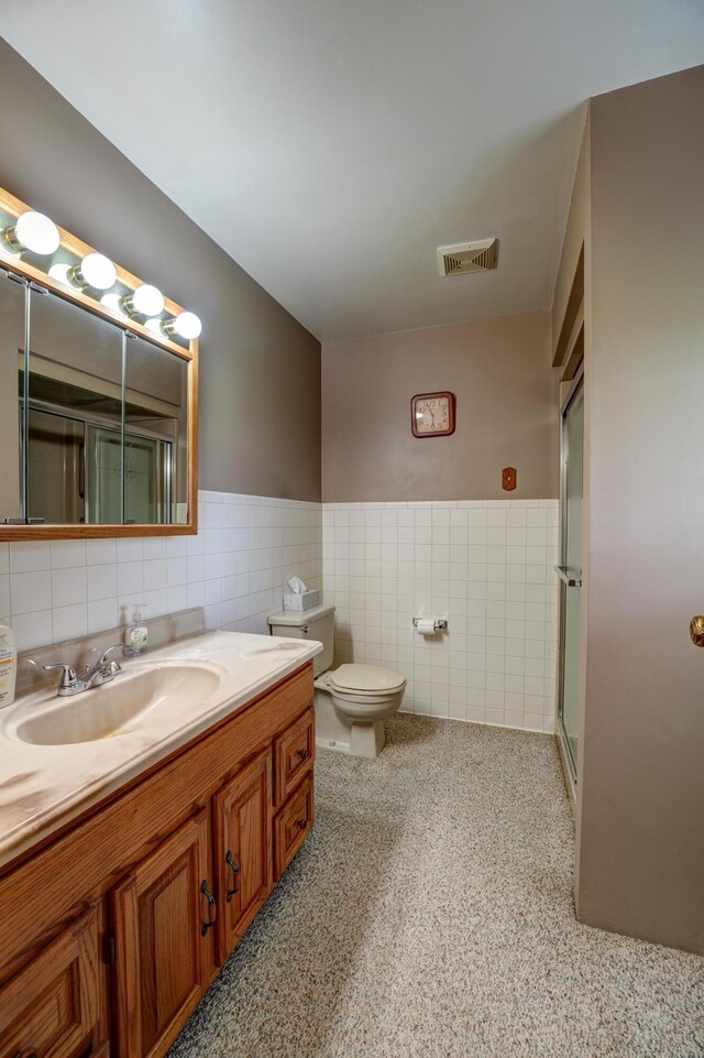 9743 State Route 118, Ansonia, OH 45303 - bathroom featuring tile walls, toilet, vanity, a shower with shower door, and a wainscoted wall