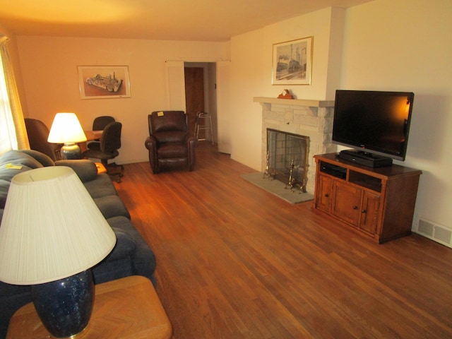 living room with dark hardwood / wood-style floors and a stone fireplace