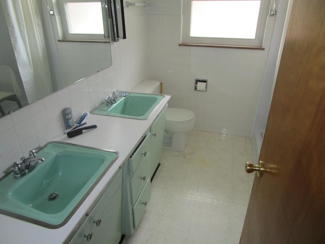 bathroom with plenty of natural light, vanity, tile walls, and toilet