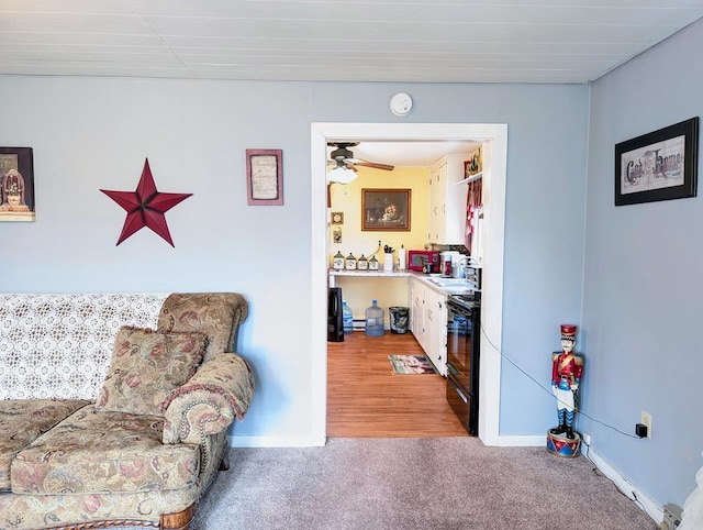 living area with baseboards, a ceiling fan, and light colored carpet