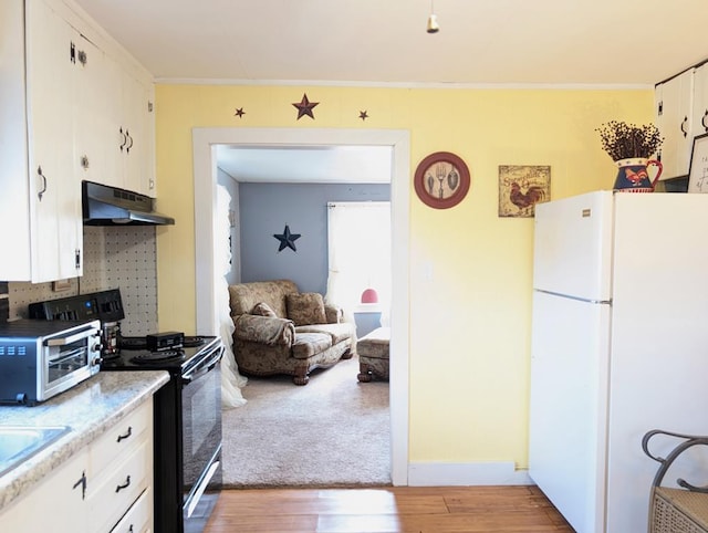 kitchen with light wood finished floors, black range with electric stovetop, freestanding refrigerator, white cabinetry, and under cabinet range hood