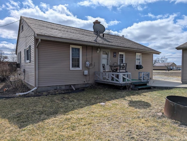 back of property featuring roof with shingles, a lawn, and a wooden deck