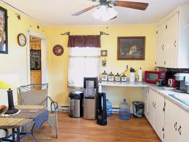 kitchen with a baseboard radiator, light countertops, light wood-style flooring, baseboard heating, and white cabinetry