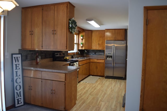 kitchen featuring tasteful backsplash, appliances with stainless steel finishes, sink, and light wood-type flooring