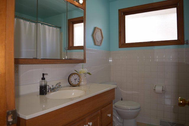 bathroom featuring vanity, tile walls, and toilet