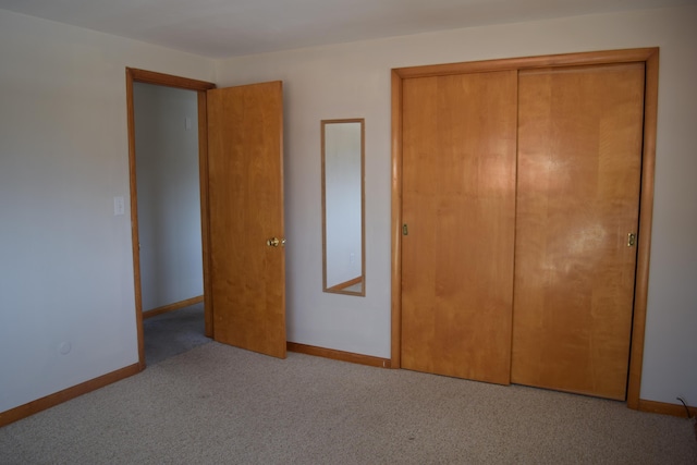 unfurnished bedroom with light colored carpet and a closet