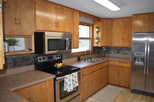 kitchen featuring sink, decorative backsplash, light hardwood / wood-style floors, and appliances with stainless steel finishes