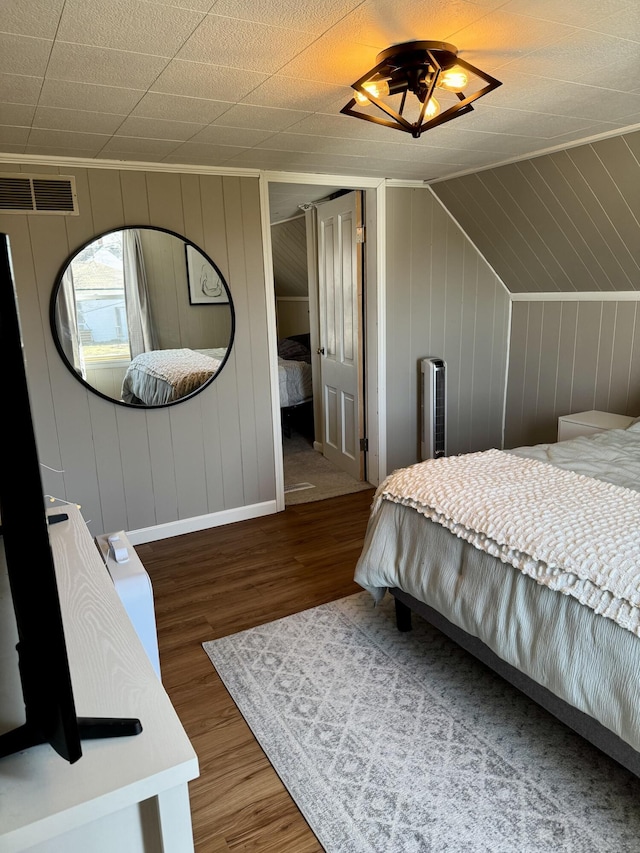 bedroom featuring visible vents, vaulted ceiling, and wood finished floors