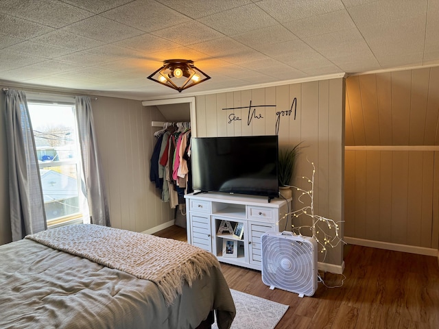 bedroom featuring a closet, baseboards, a walk in closet, and wood finished floors