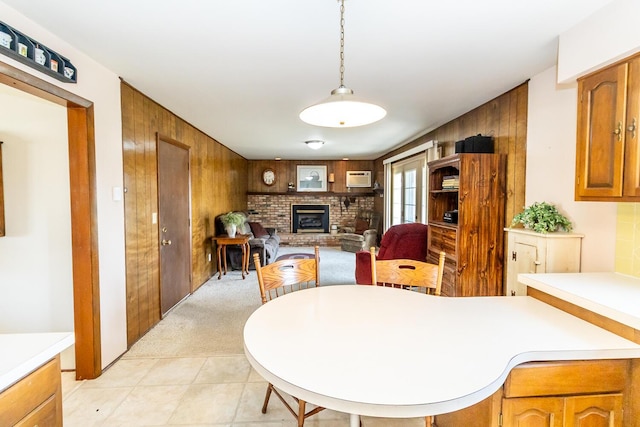 dining area featuring light carpet, wooden walls, a brick fireplace, and a wall unit AC