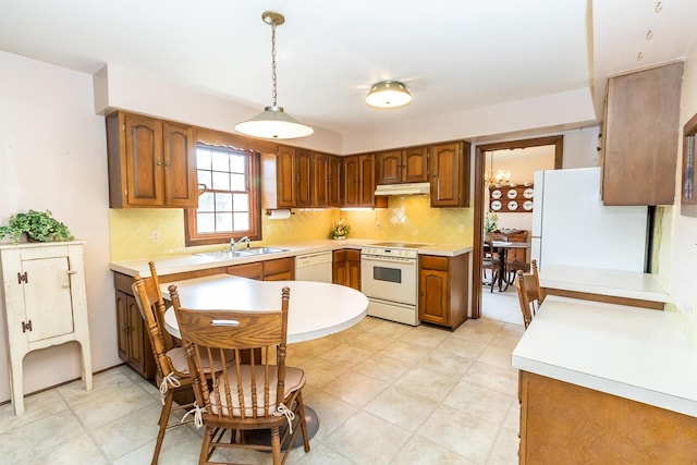 kitchen featuring under cabinet range hood, backsplash, white appliances, and a sink