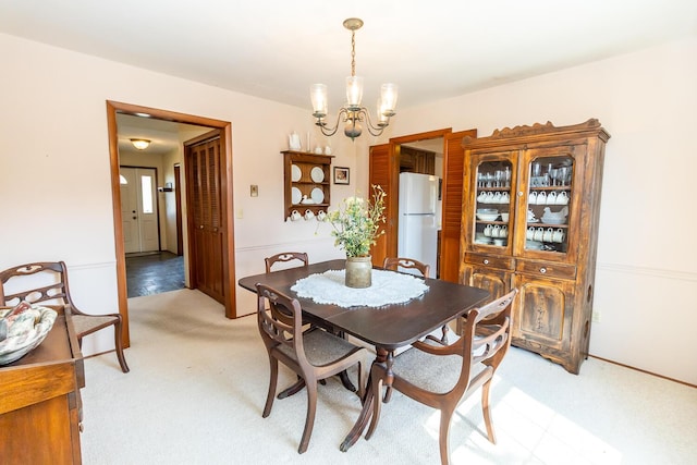 dining space featuring light colored carpet and a chandelier