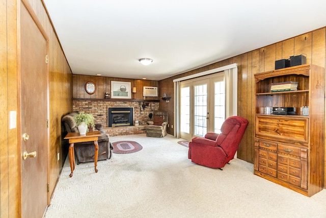 living area featuring a wall mounted air conditioner, french doors, wood walls, carpet flooring, and a brick fireplace