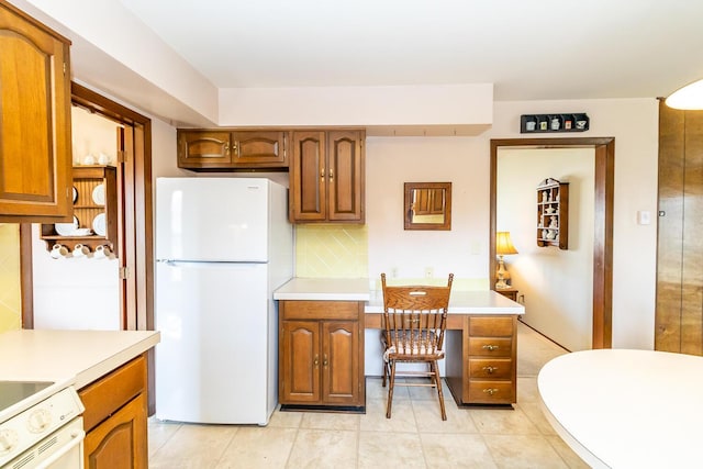 kitchen featuring white appliances, brown cabinetry, light countertops, and backsplash