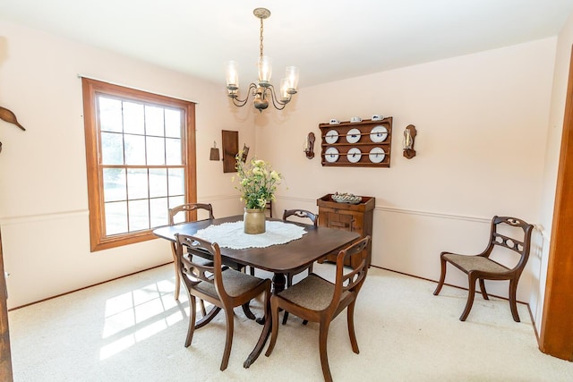 dining area with light carpet and an inviting chandelier