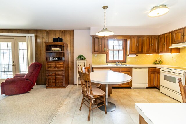 kitchen with under cabinet range hood, a sink, backsplash, white appliances, and light countertops