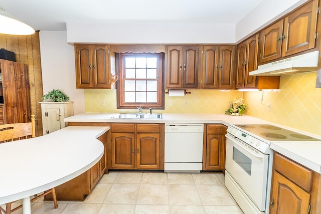 kitchen with under cabinet range hood, white appliances, light countertops, and a sink