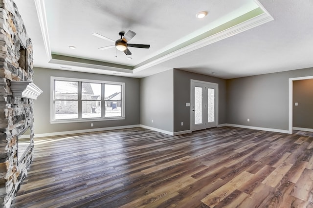 1129 Auburn St, Troy, OH 45373 - unfurnished living room featuring a ceiling fan, a stone fireplace, a tray ceiling, and a wealth of natural light